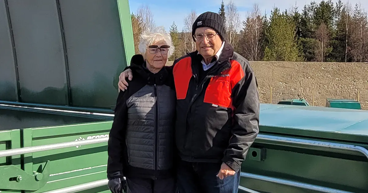 En äldre kvinna och en äldre man framför en av de gröna containrarna
