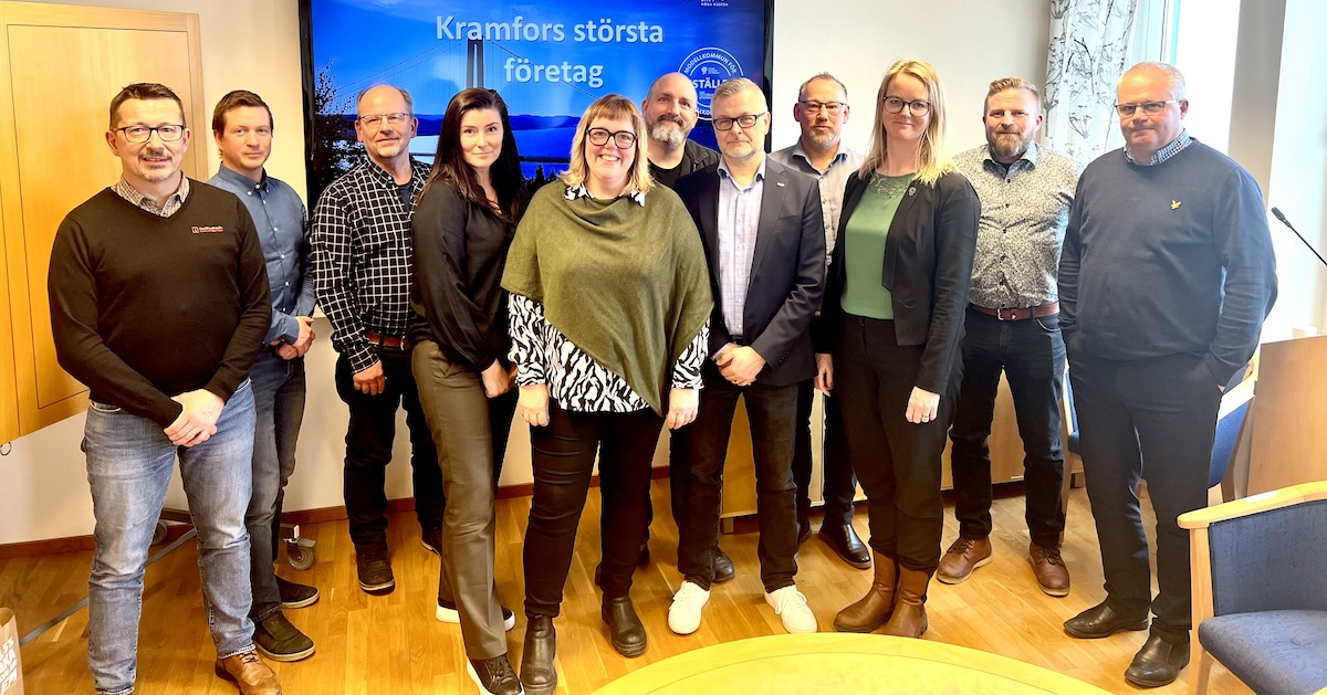en samling leende män och kvinnor framför en skärm med texten Kramfors största företag