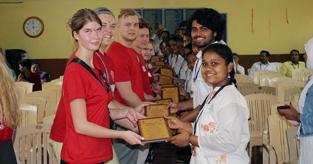 Elever från Räddningsgymnasiet står på rad tillsammans med ungdomar från Indien. De får ta emot en gåva. 