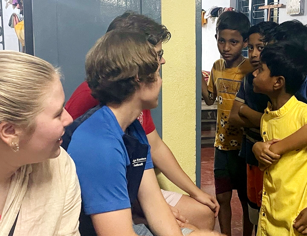 Tre svenska elever pratar med några mindre barn som går en internatatskola i Bolpur. 