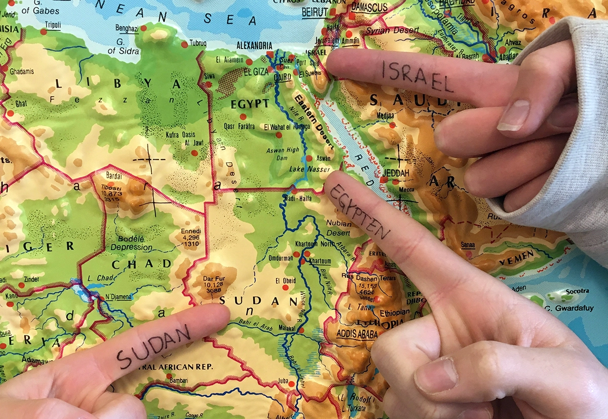 En karta över norra Afrika och tre pekfingrar som pekar. Fingrarna har texten Israel, Egypten och Sudan på sig.