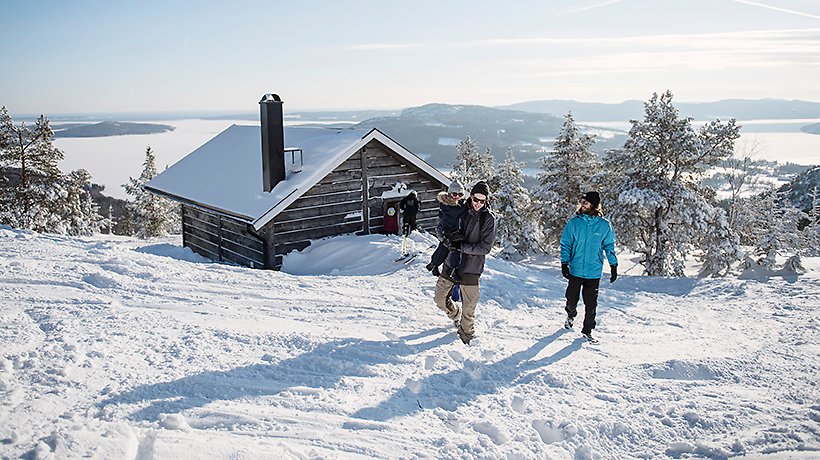 2 vuxna, 1 barn framför toppstugan Skuleberget vintertid 