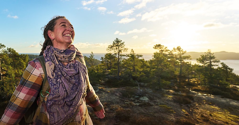 Kvinna ler mot solen på en av bergstopparna i Höga Kusten