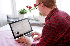 Bilden visar en person som jobbar vid en laptop.
