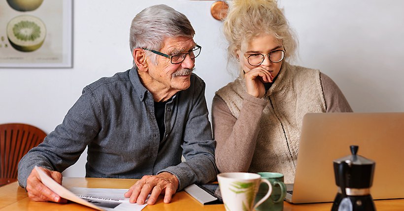 Äldre man och yngre kvinna tittar på en dator
